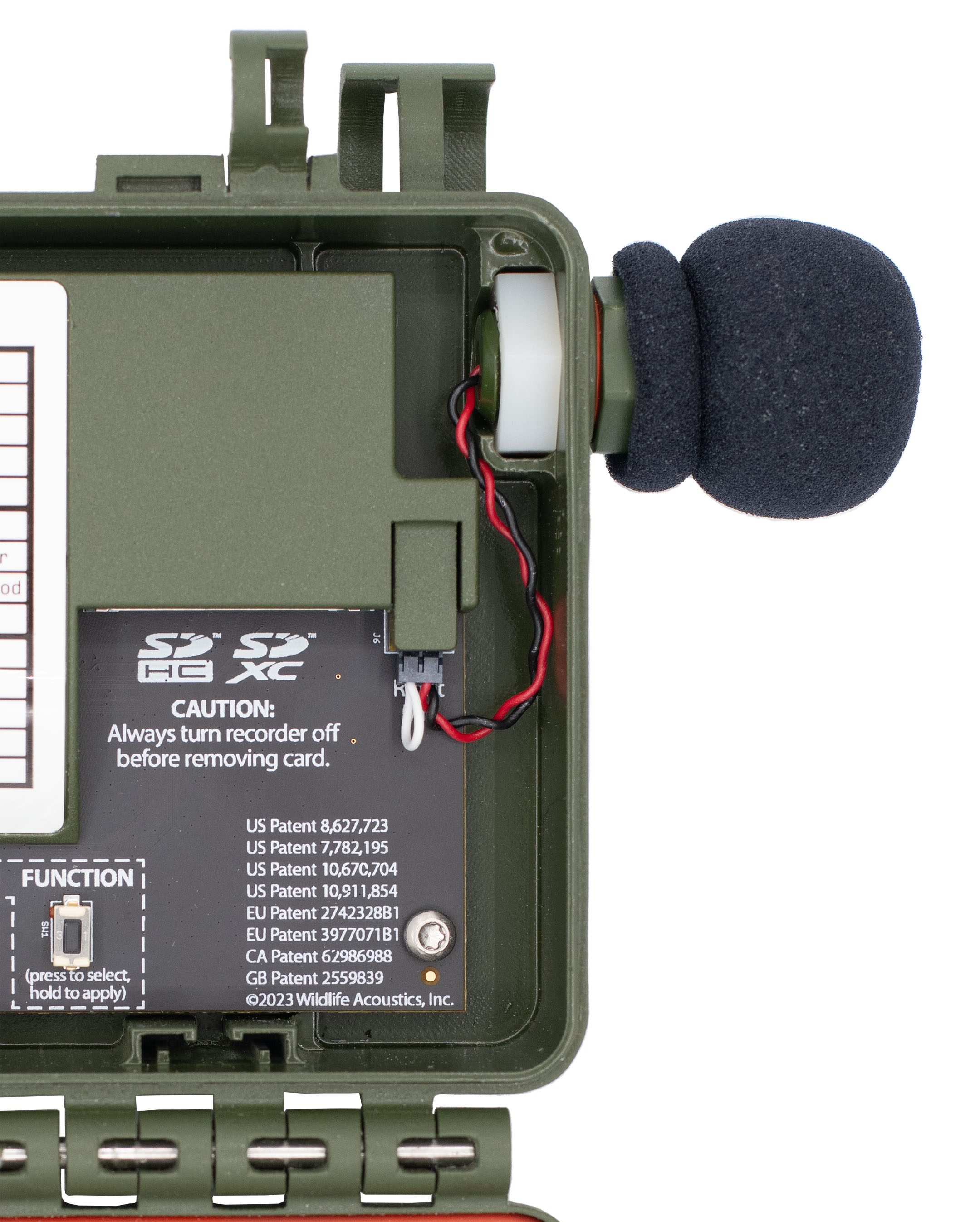 Os fios saem do conector do microfone e são dobrados para baixo e à direita, entre o slot que segura o parafuso sextavado e a cobertura plástica que protege a porta direita do microfone. Os fios são enrolados para baixo e para a esquerda para serem conectados à porta direita do microfone.